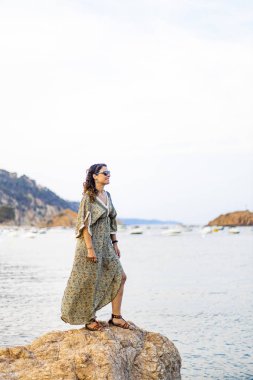 Denize yakın bir kaya üzerinde orta yaşlı kadın