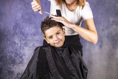 Güzel çocuk makasıyla saçını kestiriyor.