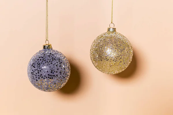 Two Christmas balls hanging on a color background