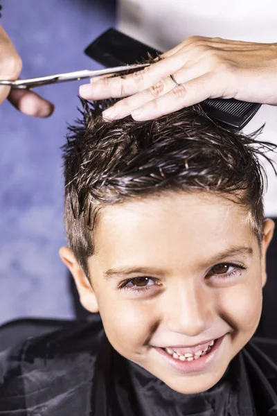 Lindo menino recebendo um corte de cabelo com tesoura — Fotografia de Stock