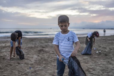 Bir grup çocuk plajda plastik topluyor. 