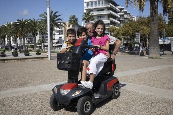 Büyükbaba ve torunları motorlu sandalyede.