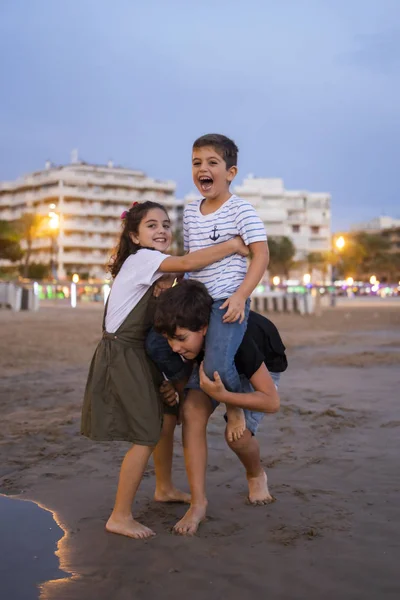 Crianças se divertem na praia ao pôr do sol — Fotografia de Stock