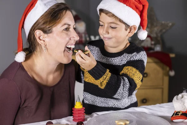 Madre e hijo degustando galletas de Navidad en casa — Foto de Stock