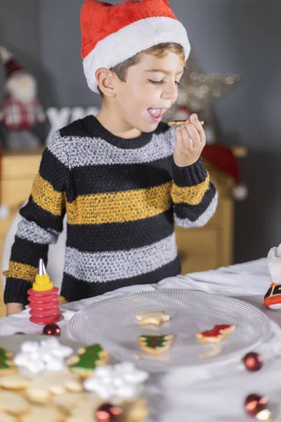 Pequeño niño degustación de galletas de Navidad en casa — Foto de Stock