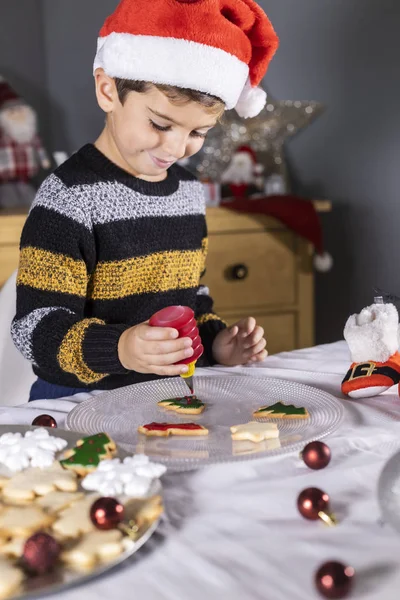 Lindo niño decorando galletas en tiempo de Navidad — Foto de Stock