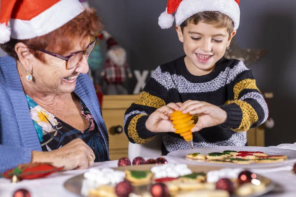 Abuela y nieto decorando galletas en Navidad — Foto de Stock