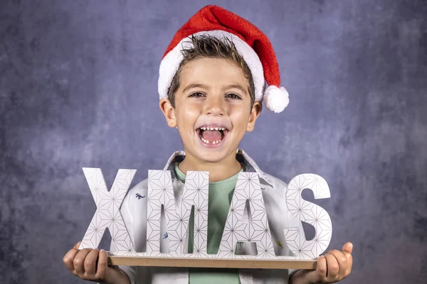 Szczęśliwe dziecko w świątecznym kapeluszu i plakacie świątecznym — Zdjęcie stockowe