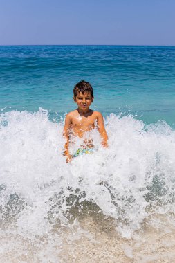 Dev bir dalganın ortasında komik bir çocuk.