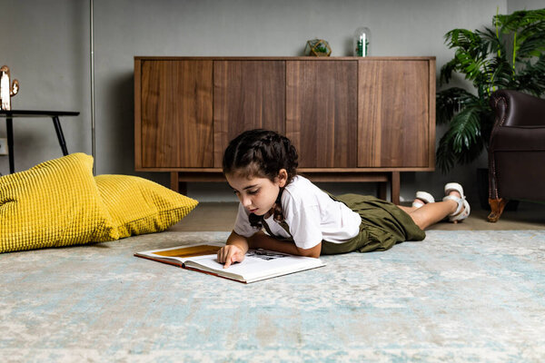 Little girl reading a book on the floor