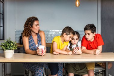 Mutlu anne çocuklarına bakıyor ve akıllı telefonla oynuyor.