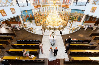 Kilise içeride. Tören gerçekleşecek. Çift yukarıdan görülebilir. Taç giyiyorlar..