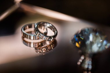 Evlilik yüzükleri. Yumuşak odaklanma. Evlilik yüzükleri elmaslarla süslenir. Ayna yüzeyinde. Ön planda yapay bir elmas var..