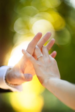 Bir çift. Birbirlerine dokunan elleri görebilirsiniz. Duygusal olarak. Evlilik yüzüğüne odaklan.