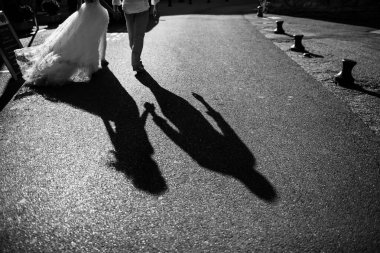 Asfalttaki bir çiftin gölgeleri. El ele tutuşuyorlar. Gölgelere odaklan.