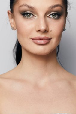 Gri arka planda, temiz ve taze derili güzel bir kadın yüzü var. Güzellik portresi. Mükemmel taze deri. Farklı duygularda model olmak. Gençlik ve cilt bakımı kavramı