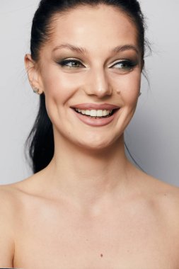 Gri arka planda, temiz ve taze derili güzel bir kadın yüzü var. Güzellik portresi. Mükemmel taze deri. Farklı duygularda model olmak. Gençlik ve cilt bakımı kavramı