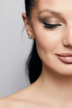 Gri arka planda, temiz ve taze derili güzel bir kadın yüzü var. Güzellik portresi. Mükemmel taze deri. Farklı duygularda model olmak. Gençlik ve cilt bakımı kavramı