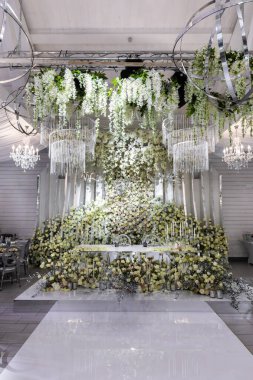 Yeni evlilerin bölgesi taze çiçekler ve süslemelerle kaplı. Çok güzel dekore edilmiş bir düğün yeri resmi.