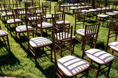 Tören için boş sandalyeler çimlerin üzerinde duruyor. Gölgeler.