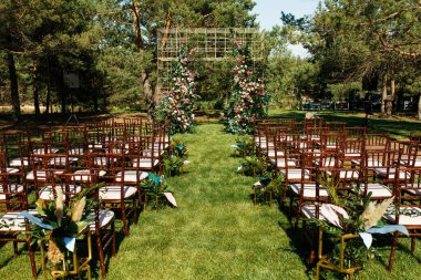 Düğün kemeri dışarıdaki tören için. Çimlerin üzerinde. Misafirler için görünür sandalyeler. Bir sürü çiçek..