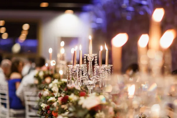 ろうそくを灯したキャンドルスティック 背景にテーブル 結婚式の会場と儀式の美しい花の装飾 — ストック写真