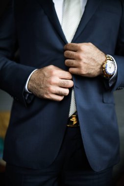 Bir adamı giydirmek. Düğmeleri bağlar. Pencerenin yanında duruyor..
