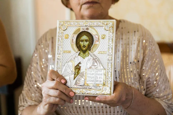 Older woman holding an icon in her hands. Traditions.