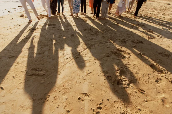 Shadows of people walking in a group. On the sand.