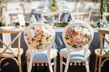 Tabaklar, bıçaklar ve çatallarla süslenmiş düğün masası, mum, yosun ve yeşillik.