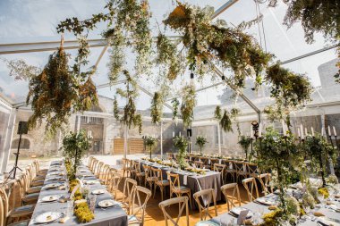 Tabaklar, bıçaklar ve çatallarla süslenmiş düğün masası, mum, yosun ve yeşillik.