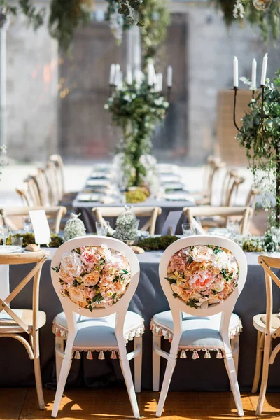 Tabaklar, bıçaklar ve çatallarla süslenmiş düğün masası, mum, yosun ve yeşillik.