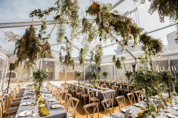 wedding table decorated by plates, knives and forks, candle, moss and greenery