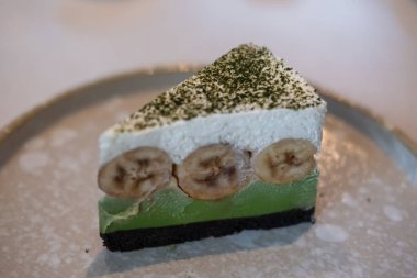 Tabakta servis edilen kibrit yeşil çay banoffee turtası. Muz, krem şanti ve parçalanmış karamelli sostan yapılmış bir tatlı..