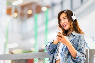 Güzel genç Asyalı kız akıllı telefon ve kulaklık gülümseme de kopya alanı kullanarak müzik dinlemek. Modern genç yaşam tarzı, üniversite öğrenci hobi, gençlik kültürü ya da cep telefonu gadget teknoloji kavramı