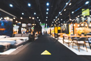 Blur, defocused background of public exhibition hall holding furniture fair event or business tradeshow. Commercial trading convention center, interior design expo, or shopping mall marketing concept