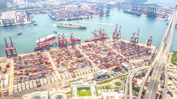 Hong Kong port industrial district with cargo container ship, cranes, car traffic on road and Stonecutters bridge. Logistic industry or freight transportation business concept