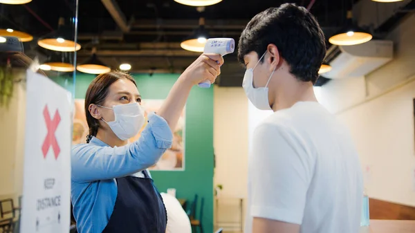 아시아 직원들은 적외선 온도계 검사기나 손님의 이마에 사용하여 입장한다 코로나 — 스톡 사진