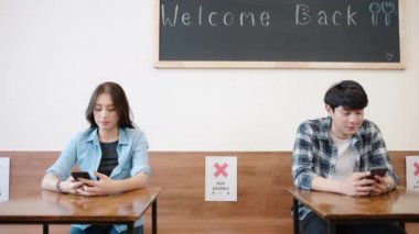 Genç Asyalı bir kadın, restoranın garsonundan menü için akıllı telefon taraması QR kodu kullanarak yemek sipariş eder. Erkek müşteri de ayrı bir mesafede oturur. Coronavirüs 'ten sonraki yeni normal sosyal mesafeli yaşam tarzı