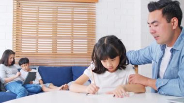 Asyalı ebeveynler çocuklarını evde eğitiyorlar. Baba kızına dizüstü bilgisayar öğretiyor, anne oğluna dijital tabletle öğretiyor. Yeni normal yaşam tarzı, aile ilişkisi, çocuk eğitim konsepti