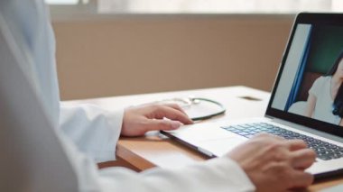 Doktor online video araması tedaviyi açıklıyor. Hastanedeki dizüstü bilgisayarla evden bağlanan Asyalı hasta ile semptom kontrolü. Telemedikal, Covid-19 yeni normal sağlık hizmeti kavramı