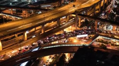 Otobanda, kavşakta, gökyüzü tren yolunda, gece inşaat alanının altında araba trafiğinin hızlandırılması. Şehir taşımacılığı, Asya şehir hayatı. Yüksek açılı şehir manzarası