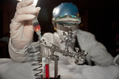 Bilim adamları şırıngayı test tüpüne sokup plazma covid-19 aşısı arıyor.