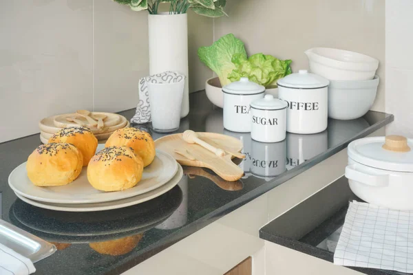 厨房内黑色工作台上配有白色陶瓷餐具的盘子上的美味面包 — 图库照片