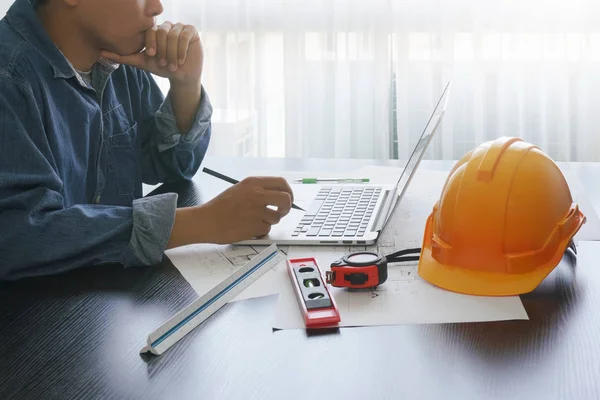 architect working on table with laptop and construction tools - business and industrial concept