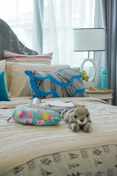 Doll and neck pillow on bed in cozy style interior bedroom