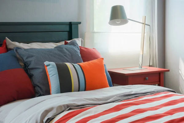 Clorful poduszki na łóżku z czerwonym kocem w paski w nowoczesnych interi — Zdjęcie stockowe