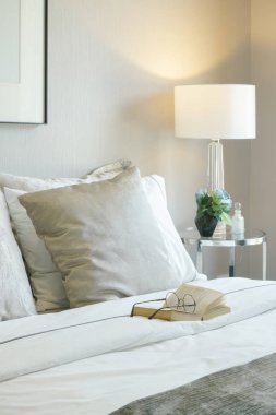 Modern iç yatak odasında yatakta gözlük ve kitap