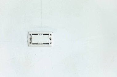 Yeni beyaz duvarda kapak plakası olmayan elektrik anahtarı