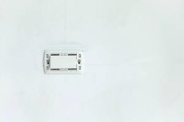 Den elektriska brytaren utan täckplåt på den vita väggen i den nya Royaltyfria Stockbilder